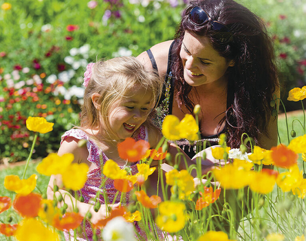Mother and daughter smell flowers in Queens Park